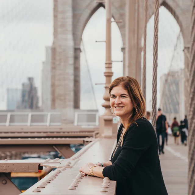 Deb Swacker, a Fora Advisor, smiles from the Brooklyn Bridge in New York City