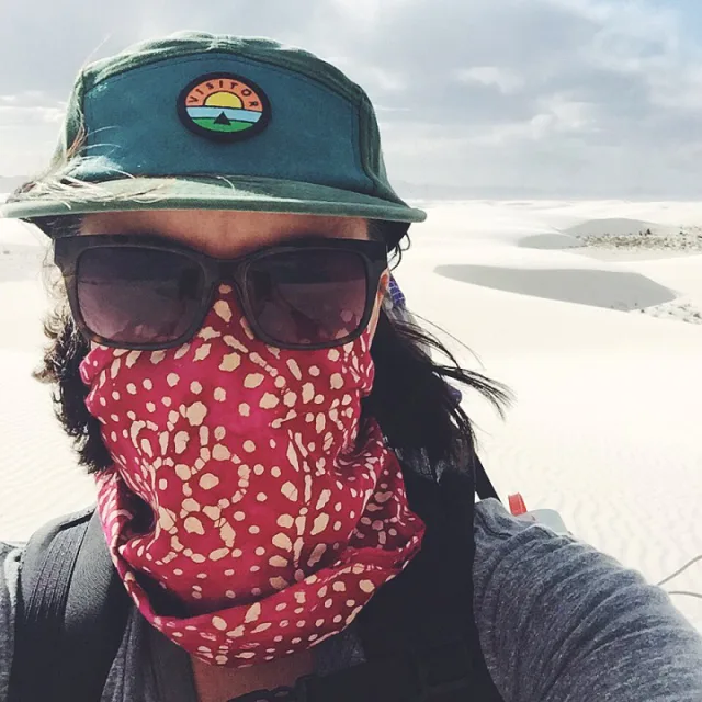 Travel Advisor Melissa Clark wearing p cap, sunglasses and handkerchief on her face in a desert. 