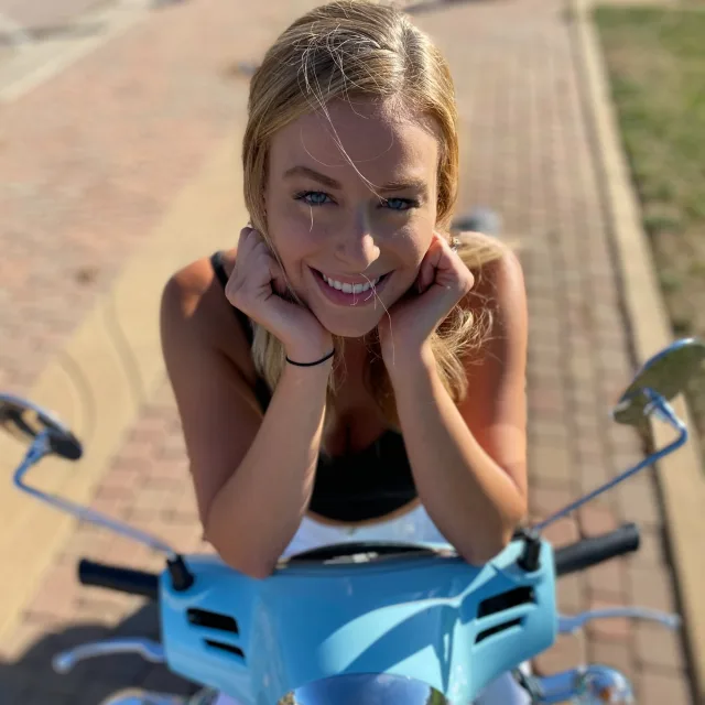 Travel advisor Kelsey Ribblett smiles on a blue moped