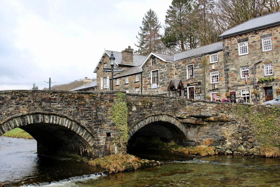 Bridge on water with brown brick building at the back.