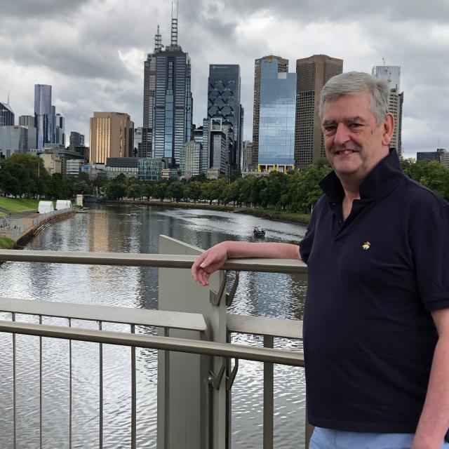 Man smiling in front of buildings and river