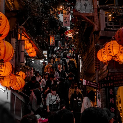bustling narrow street lined with lantern lights and shops