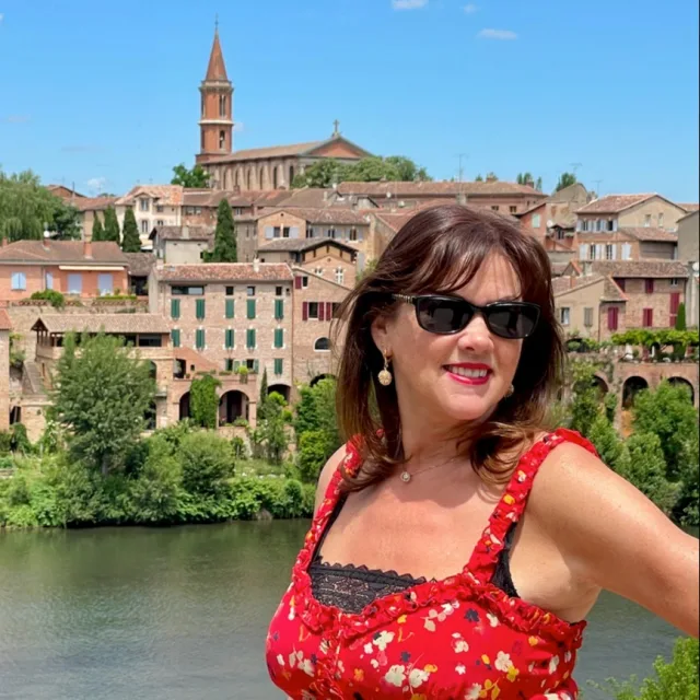 Travel Advisor Julia Rees in a red dress in front of a city. 
