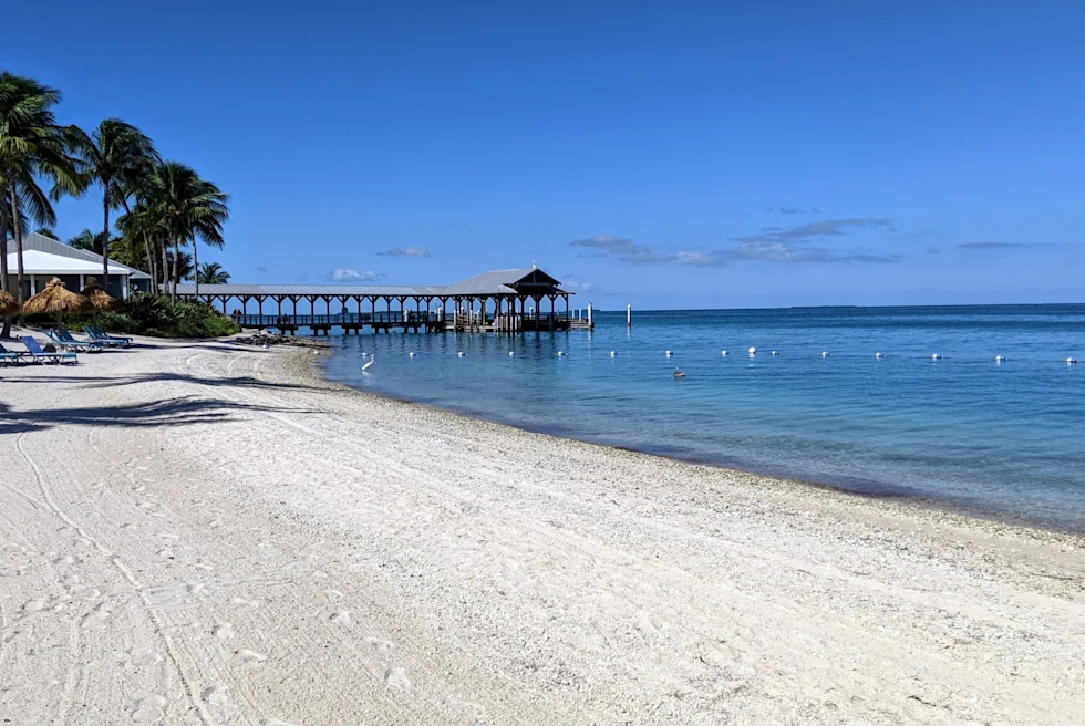 white-sand beach with a pier leading out into the sea