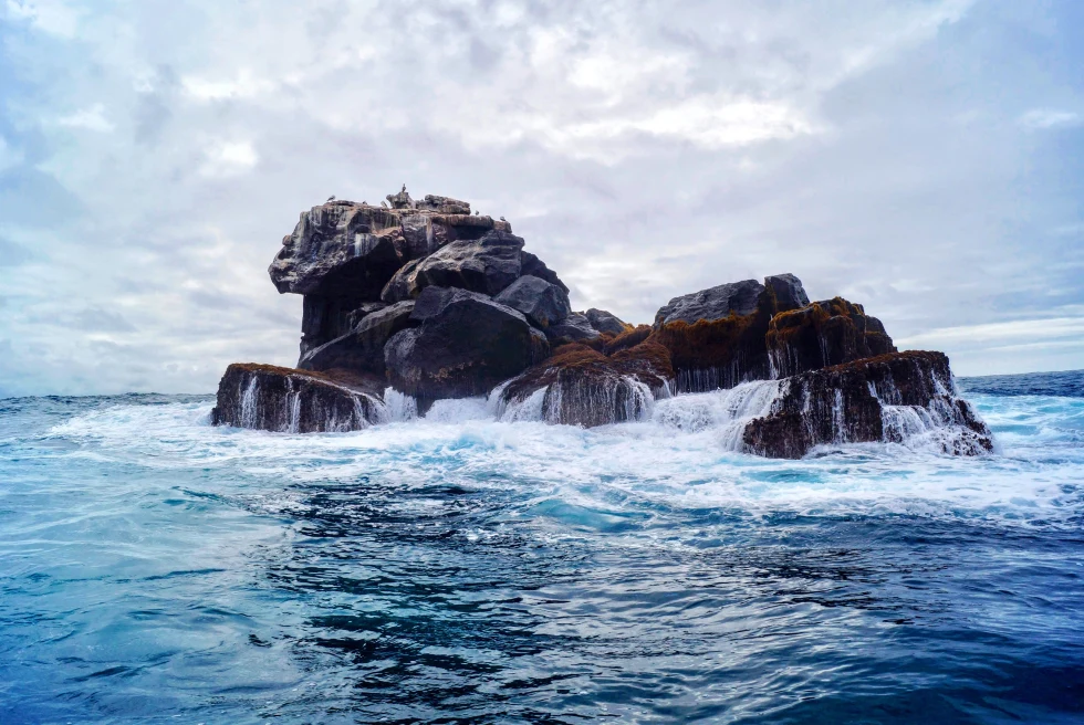 View of rocks in the ocean with a cloudy sky in the Galapagos Islands