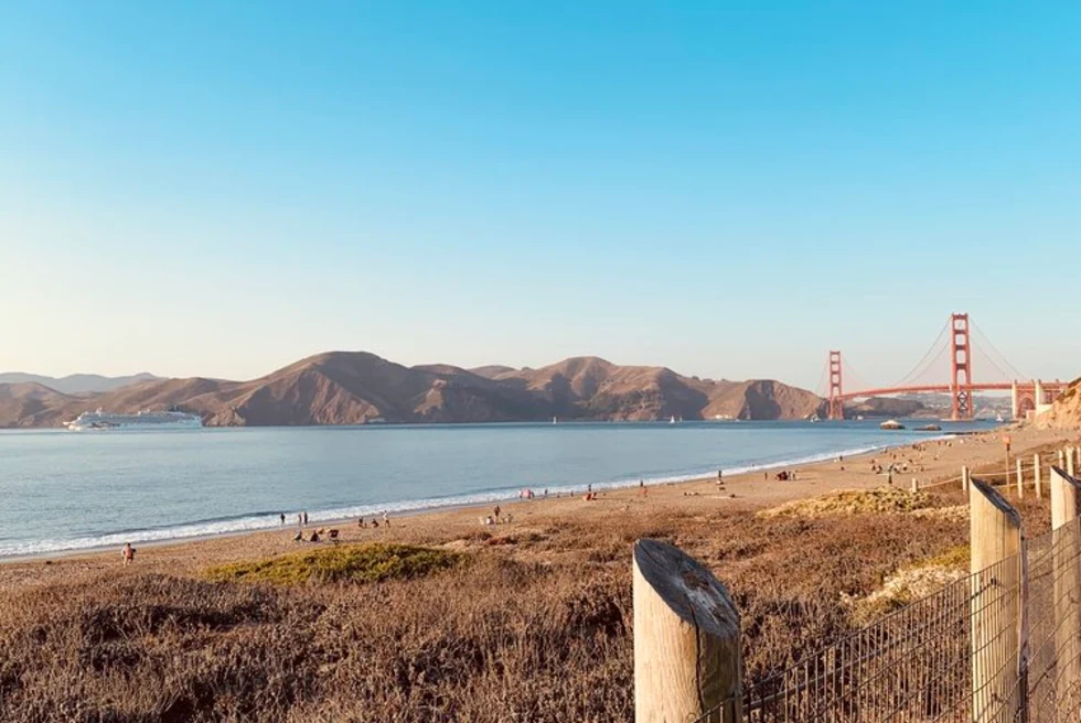 fence next to land with body of water and bridge in the distance