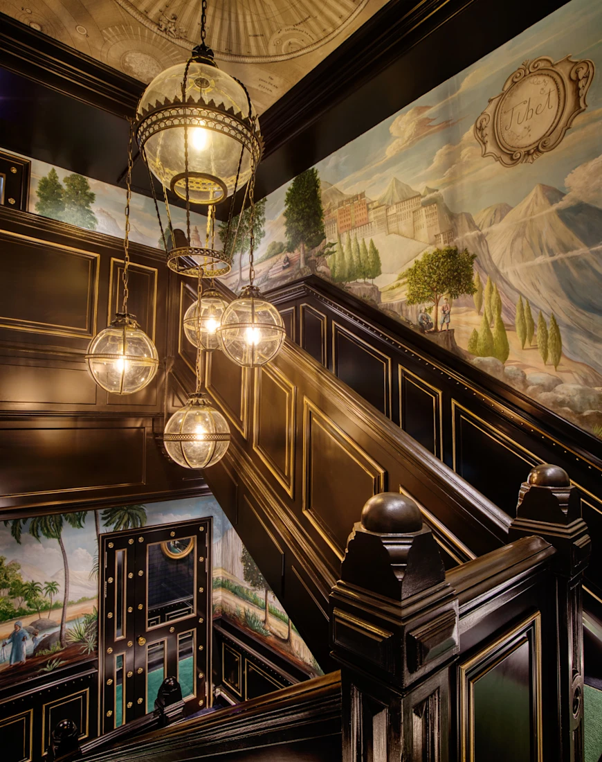 a handsome staircase in a building with colorful wallpaper and hanging globe lights