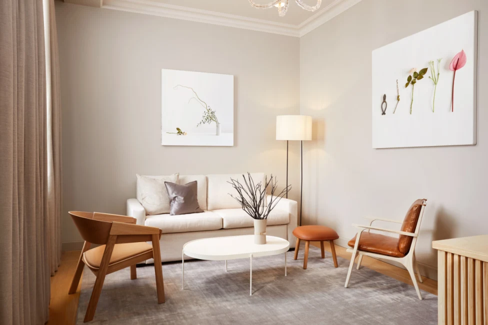 a chic living space with brown modern leather chairs, a white couch beside a lamp, and a painting depicting flowers