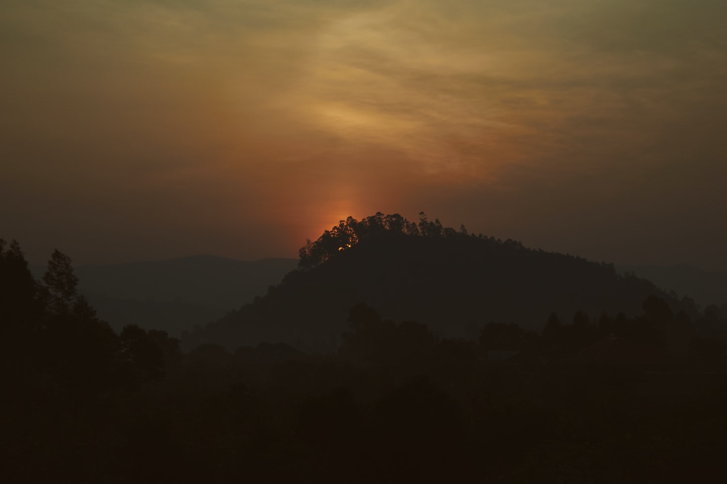outline of mountain in rwanda africa with orange sun rising 