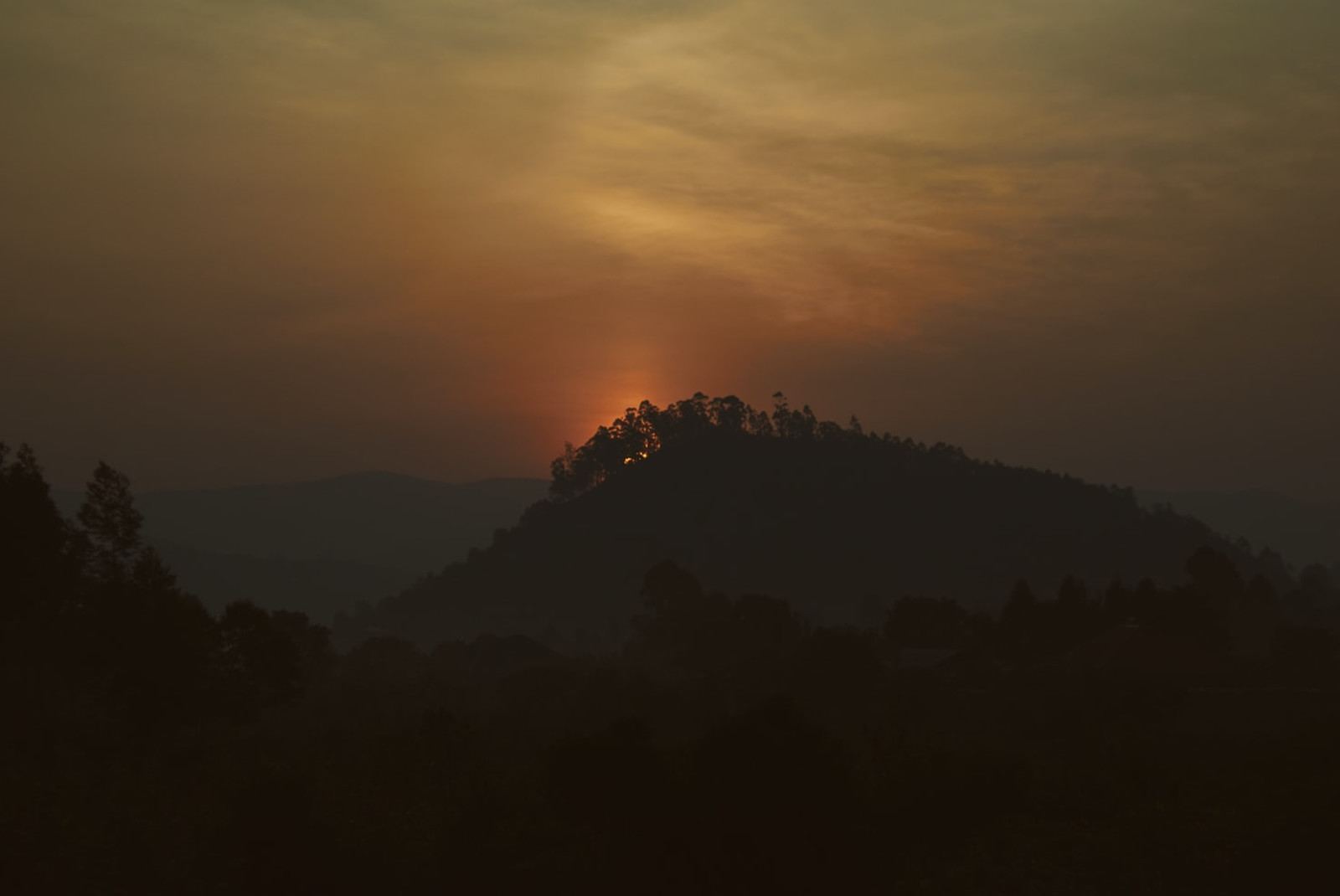 outline of mountain in rwanda africa with orange sun rising 