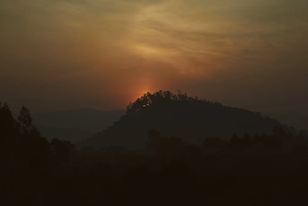 outline of mountain in rwanda africa with orange sun rising 