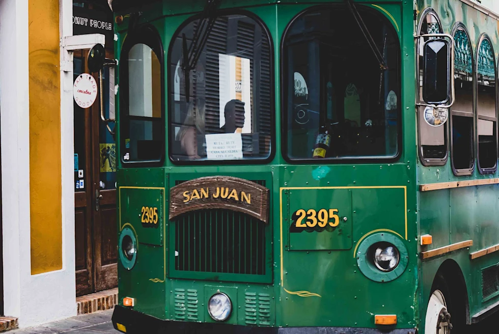 Green bus on the street next to a yellow building during daytime