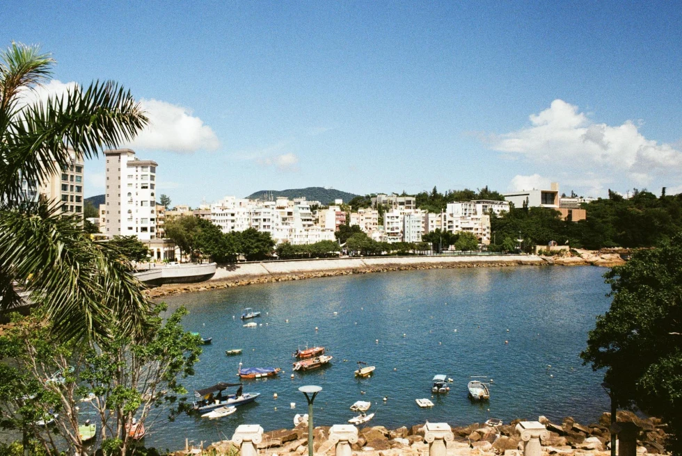 a costal town on a sunny day with boats in the harbor and a mountain range in the distance