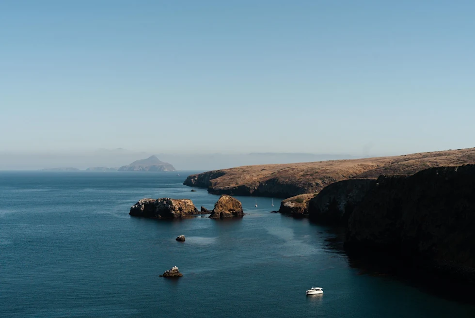 landscape of still blue water off islands with boats traveling to and from