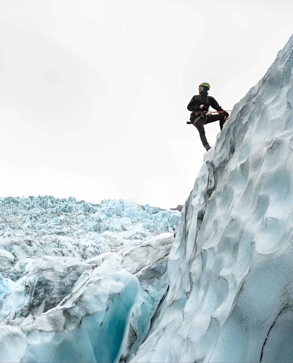 a person in all black stands on an ice cliff