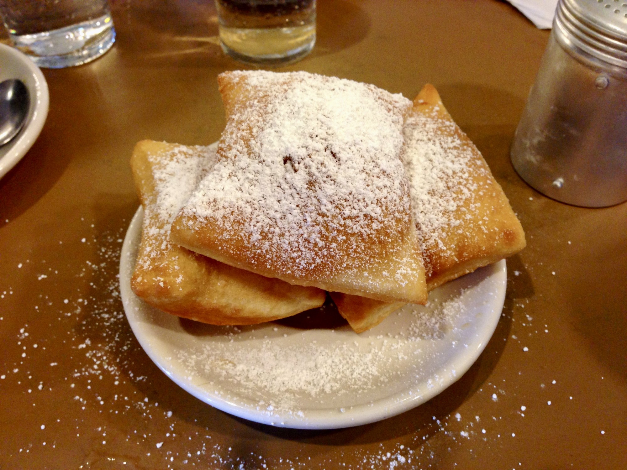 A plate with three puffs sprinkled with powdered white sugar.