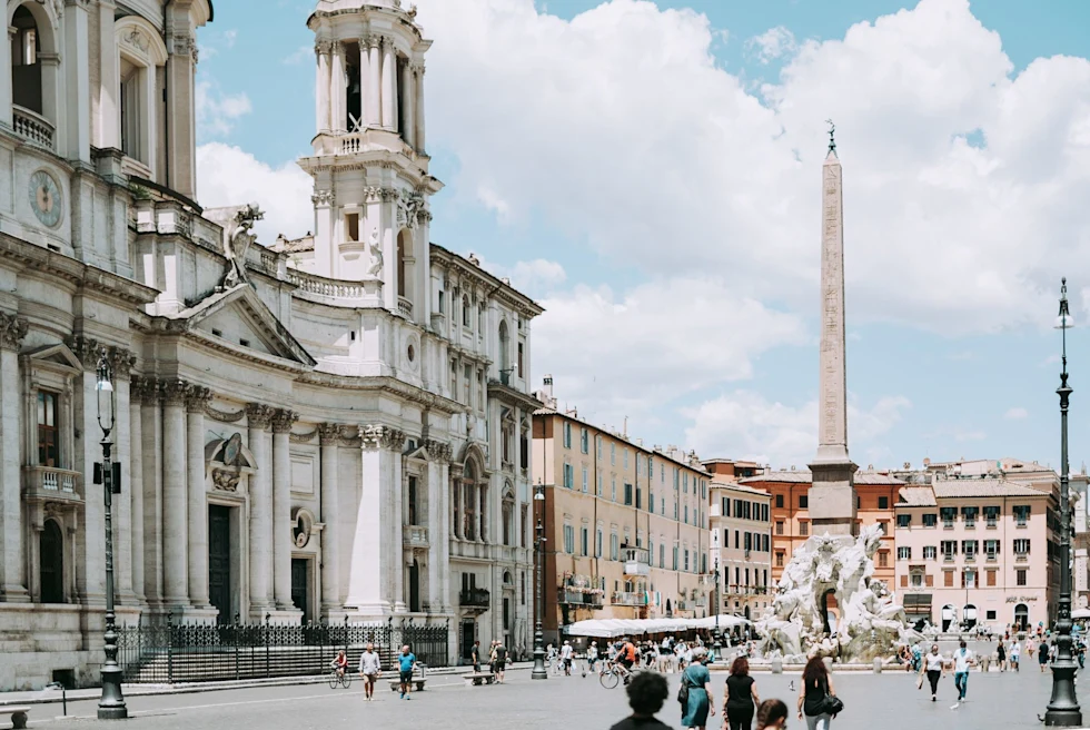 a palazzo on a sunny day with a large spire landmark in the middle a fountain sculpture
