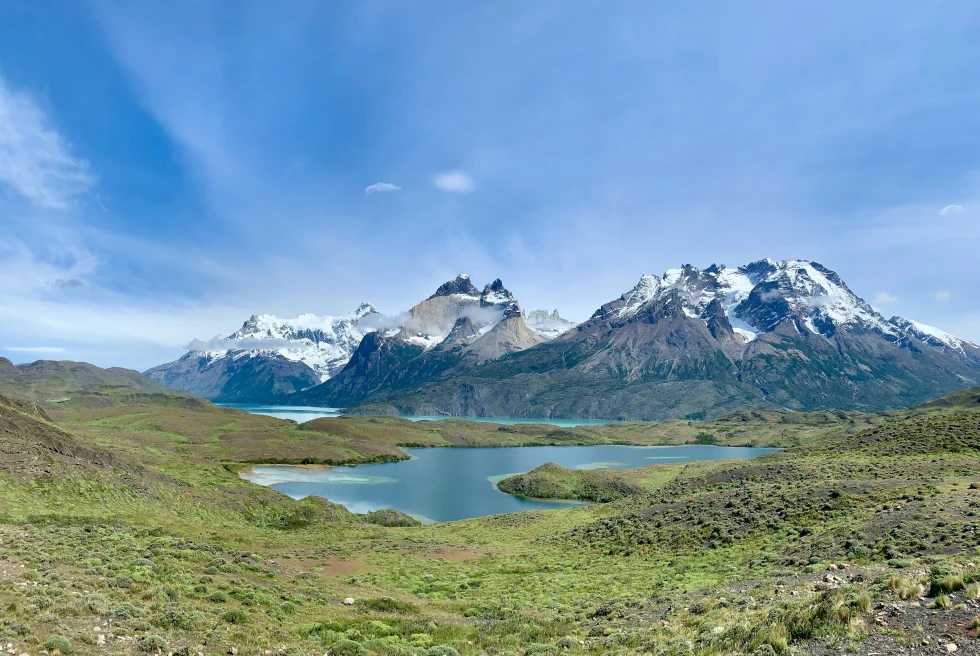 snowy mountains over green fields and lake