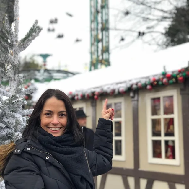 Travel Advisor Mindy L. Weiss pointing at a tan house with snow on the roof.