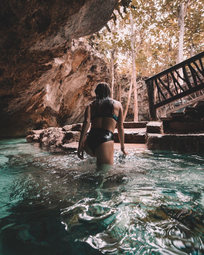 Woman in water walking towards stairs in Cenote in Mexico