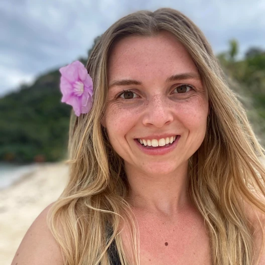Travel Advisor McKenley Stewart on a beach with a pink flower in her blonde hair.