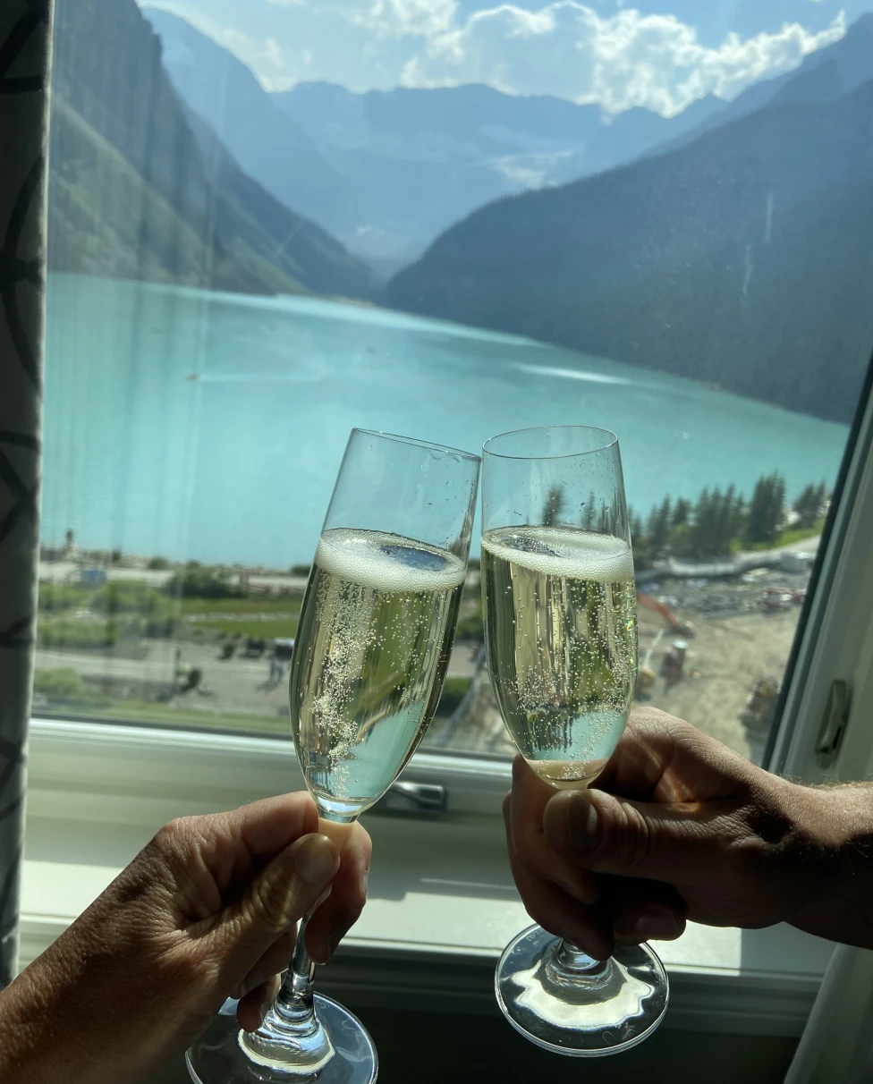 Two wine glasses being tossed in front of a lake.