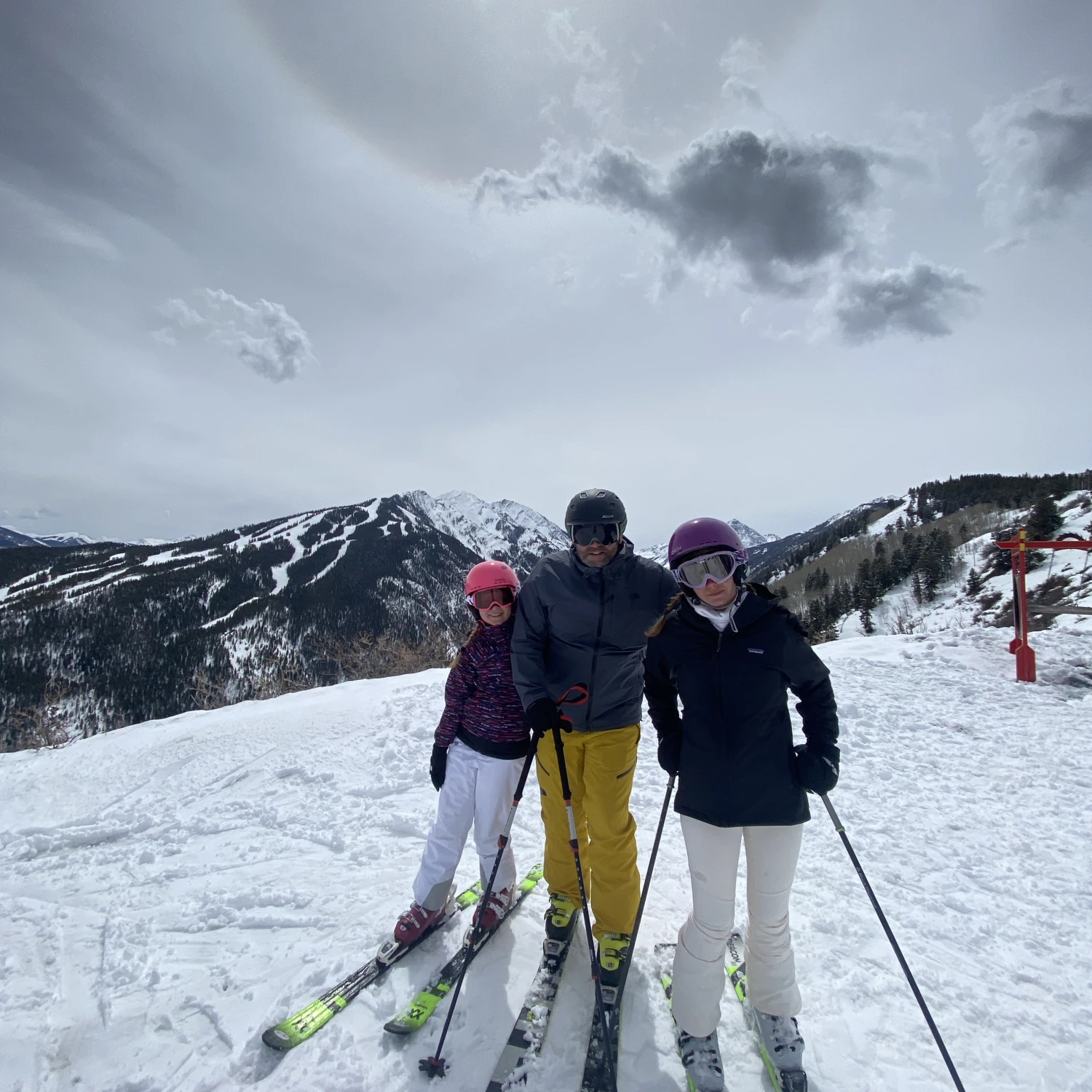 three people skiing in the snow with mountains in the background