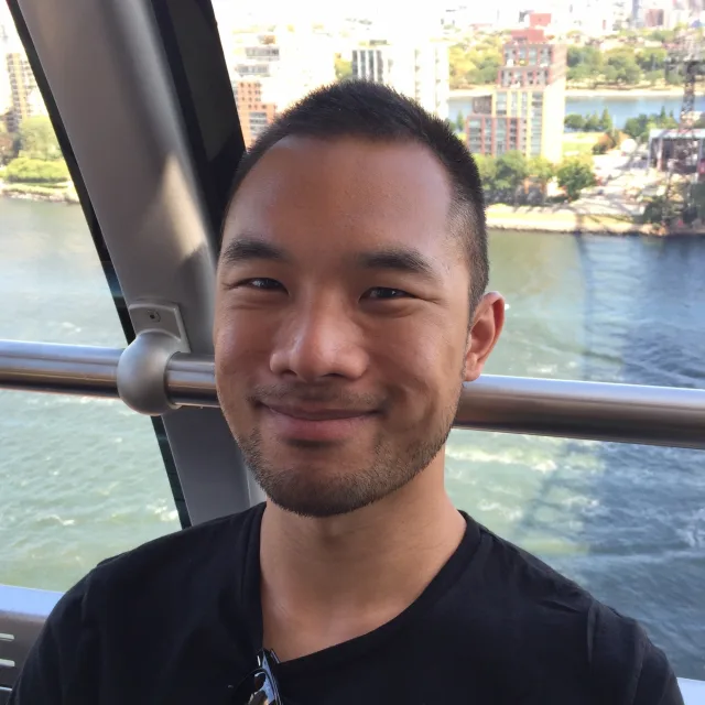 Travel Advisor Al Tan smiles wearing a black shirt with sun glasses tucked into the collar on a boat ride 