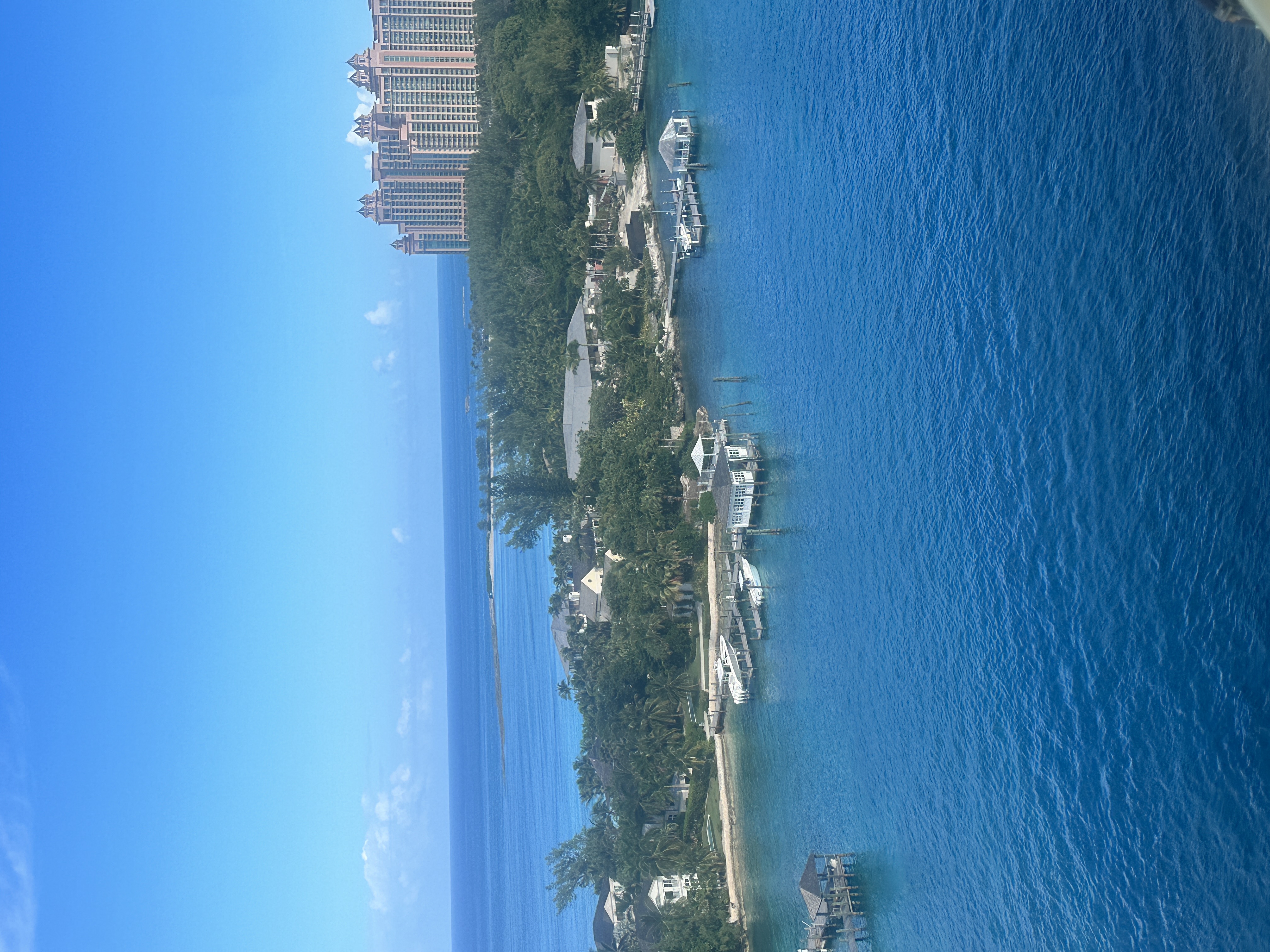 An aerial view of blue sea water surrounding a harbor with a resort building to the right