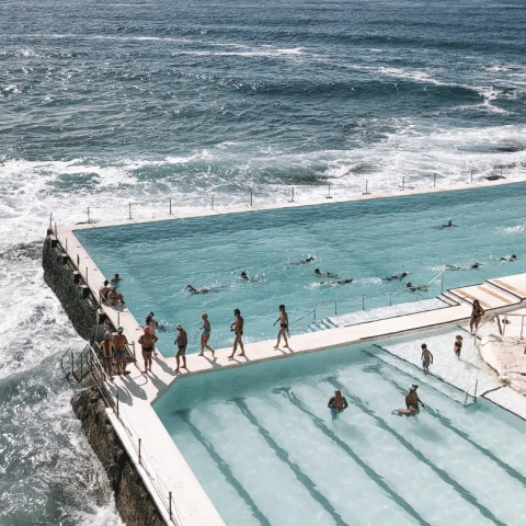 A view of people standing near a swimming pool and ocean.