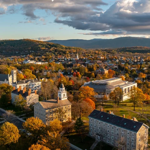 An aerial view of a autumnal town with mountains in the background. 