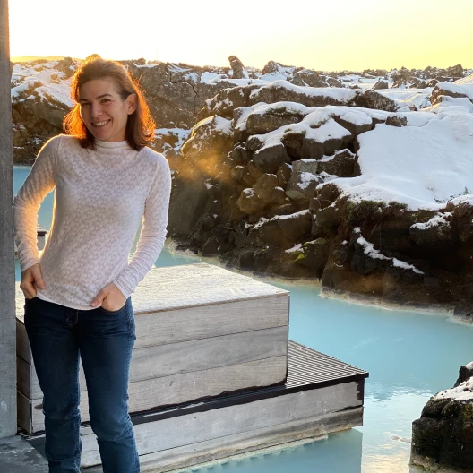 Travel Advisor Melissa Friedman-Levine wearing a white sweater and jeans with snow clad mountains in the background. 