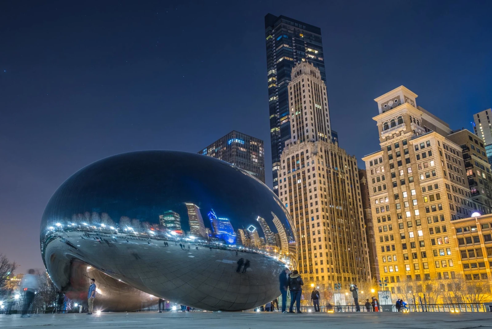 the famous bean sculpture of Chicago's Millennium Park reflects the downtown city scape at night 