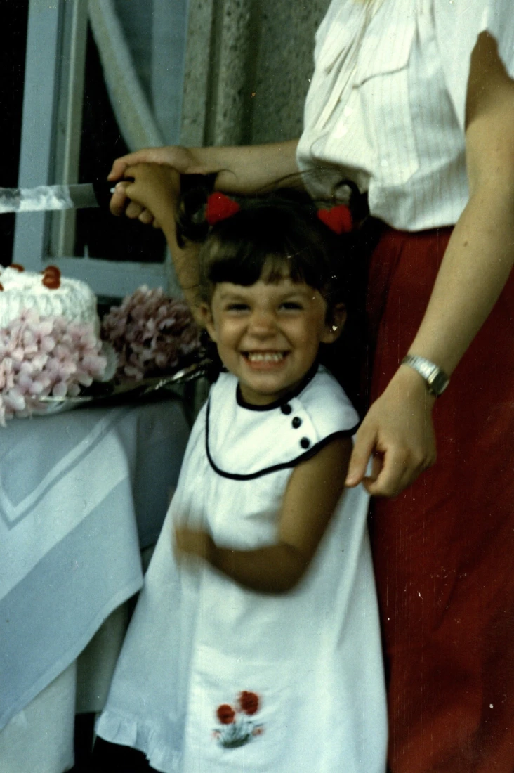 a young child in a white dress smiles