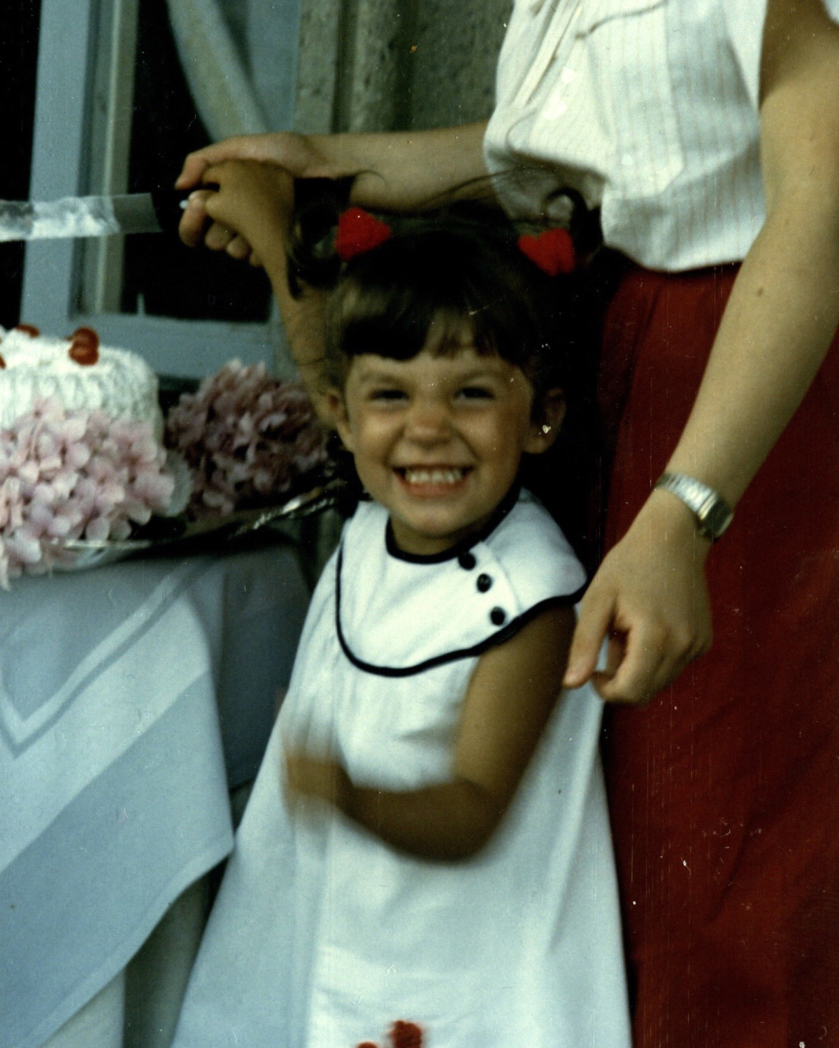 a young child in a white dress smiles