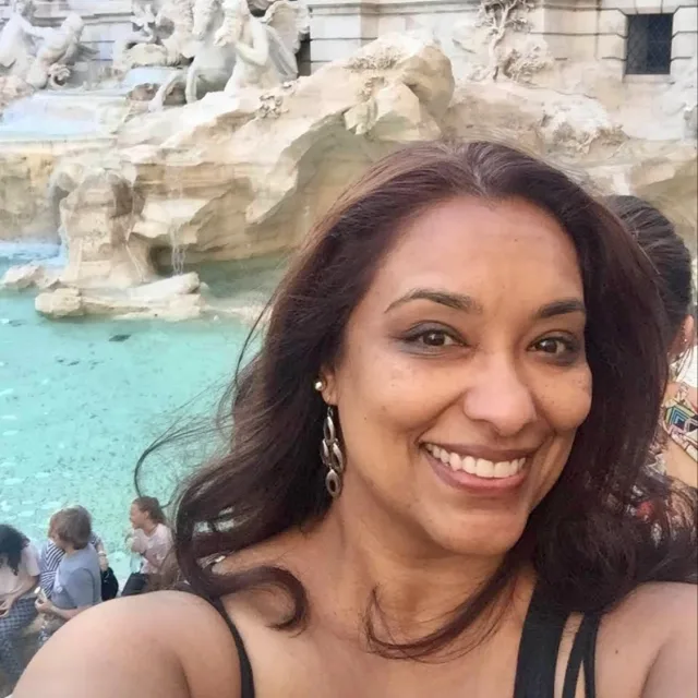 Travel advisor Vyanti Joseph smiles in front of a classical statue and fountain.