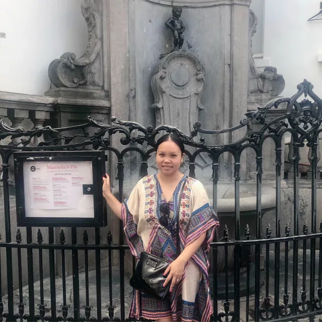 Travel Advisor Yani Asari in a kaftan shirt with black bag in front of a historic monument. 