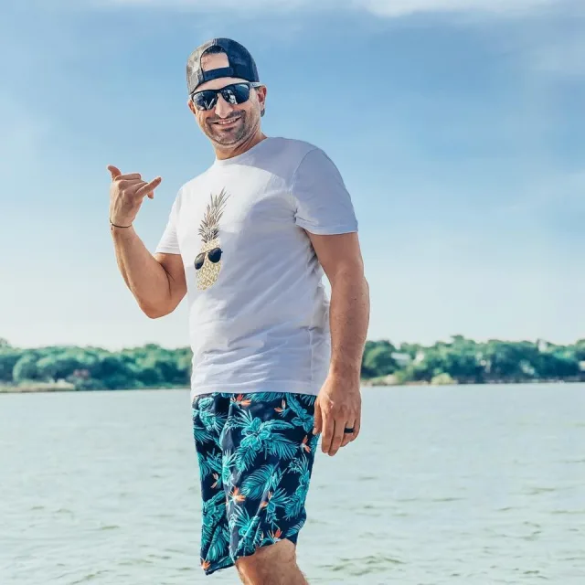 Travel Advisor Nicholas Kohlhepp in a white shirt and blue swim trunks standing in front of the water.