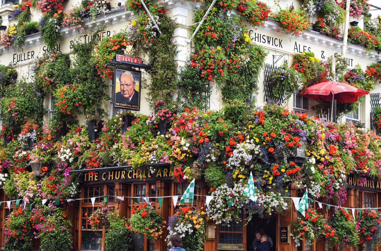 The Churchill Arms pub in London, England covered in green, pink, white and yellow flowers. 