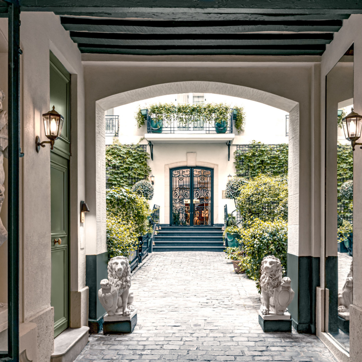 The chic entryway of Relais Christine, in Paris, with white statues and well-groomed greenery