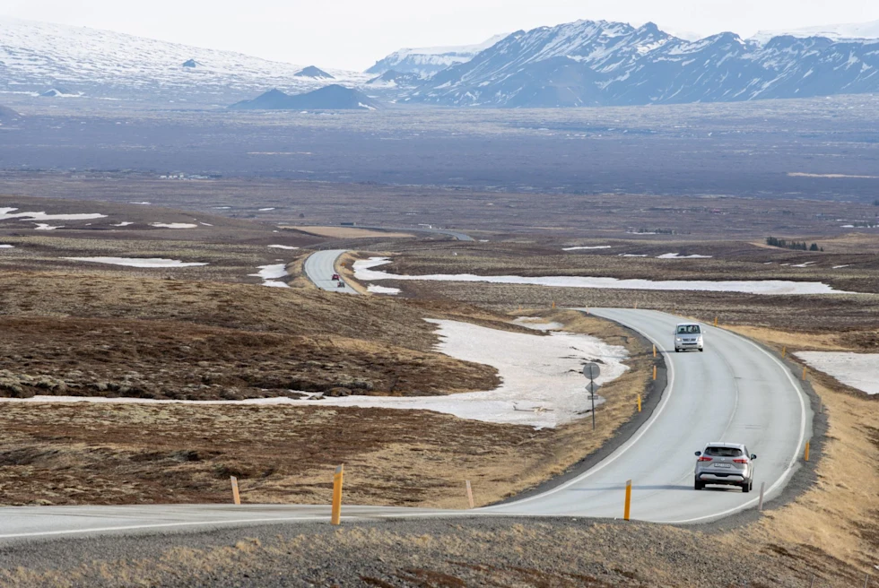 Road with cars and snow covered mountains at the back.