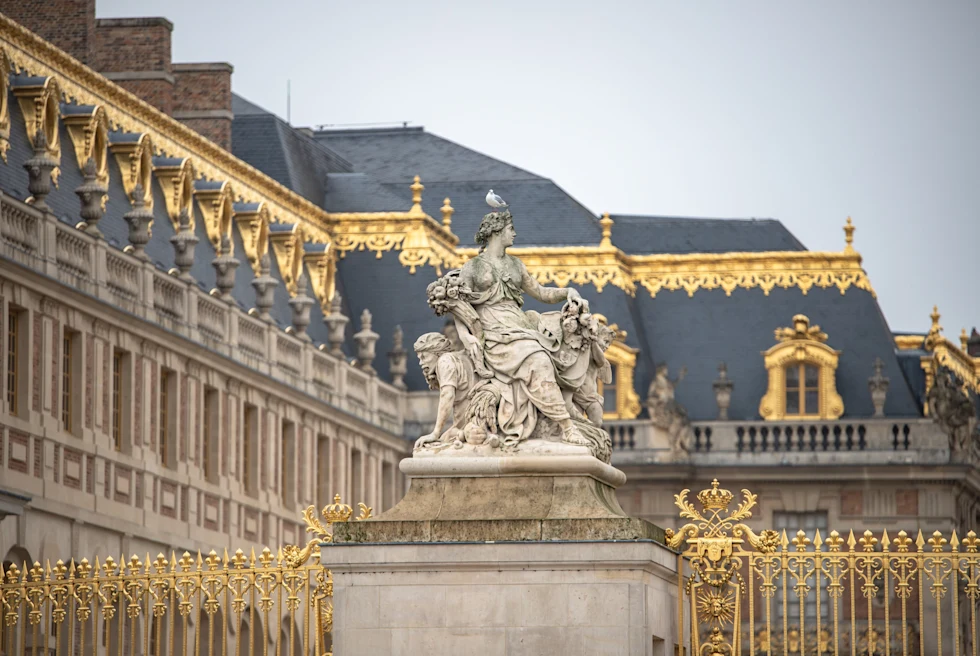 Gray and golden stones building with a statue in front of it