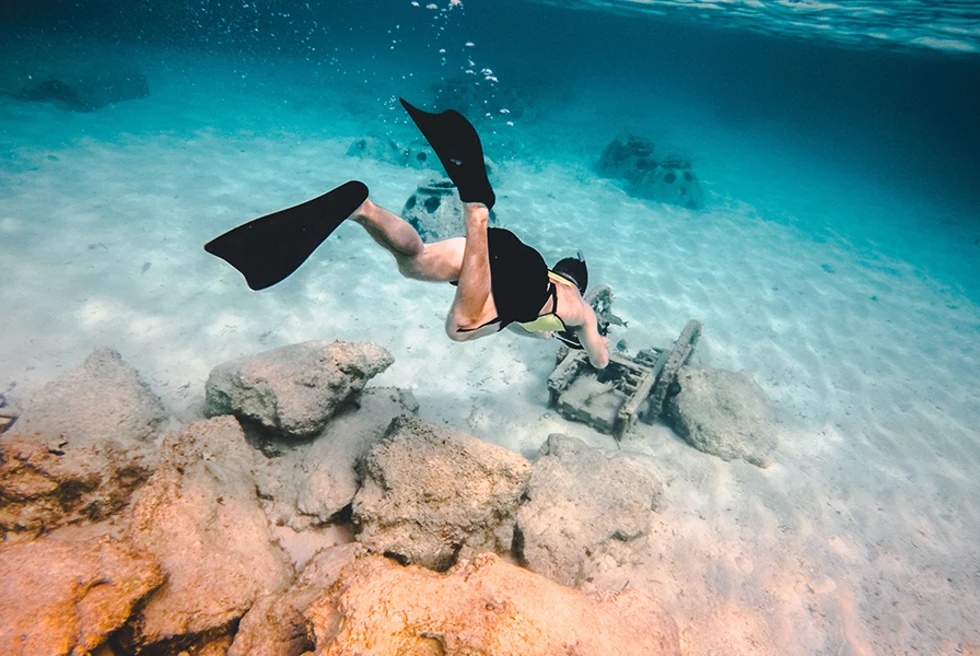 Man snorkeling in shallow blue water.