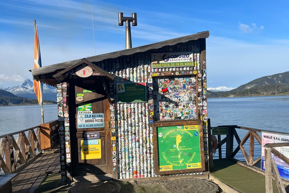 small post office covered in stickers and stamps on a lake