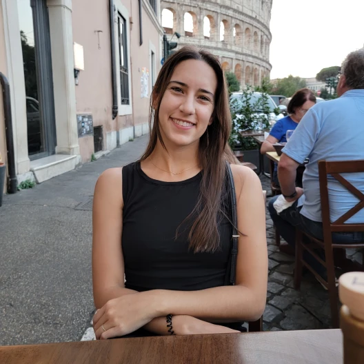 Travel advisor Danielle Sadovyi smiling at a table in front of the colosseum while on vacation.