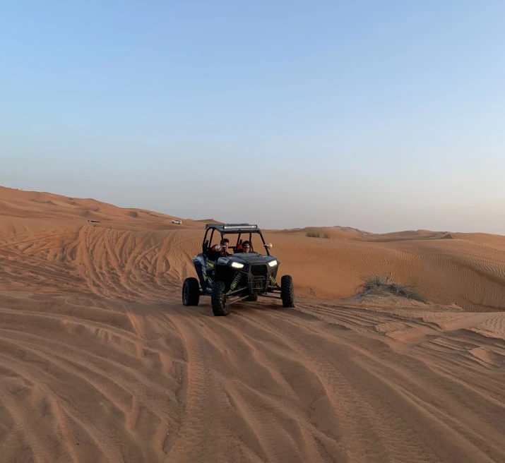 an atv on the sand in the desert with a cloudless sky