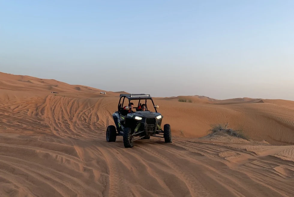 an atv on the sand in the desert with a cloudless sky