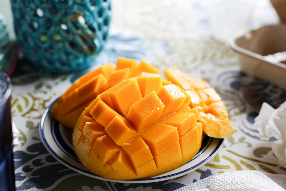bright yellow mango cut into square pieces on a small plate