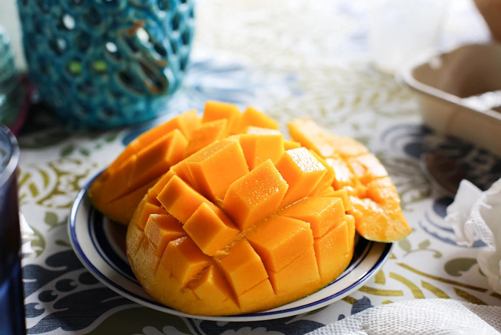 bright yellow mango cut into square pieces on a small plate