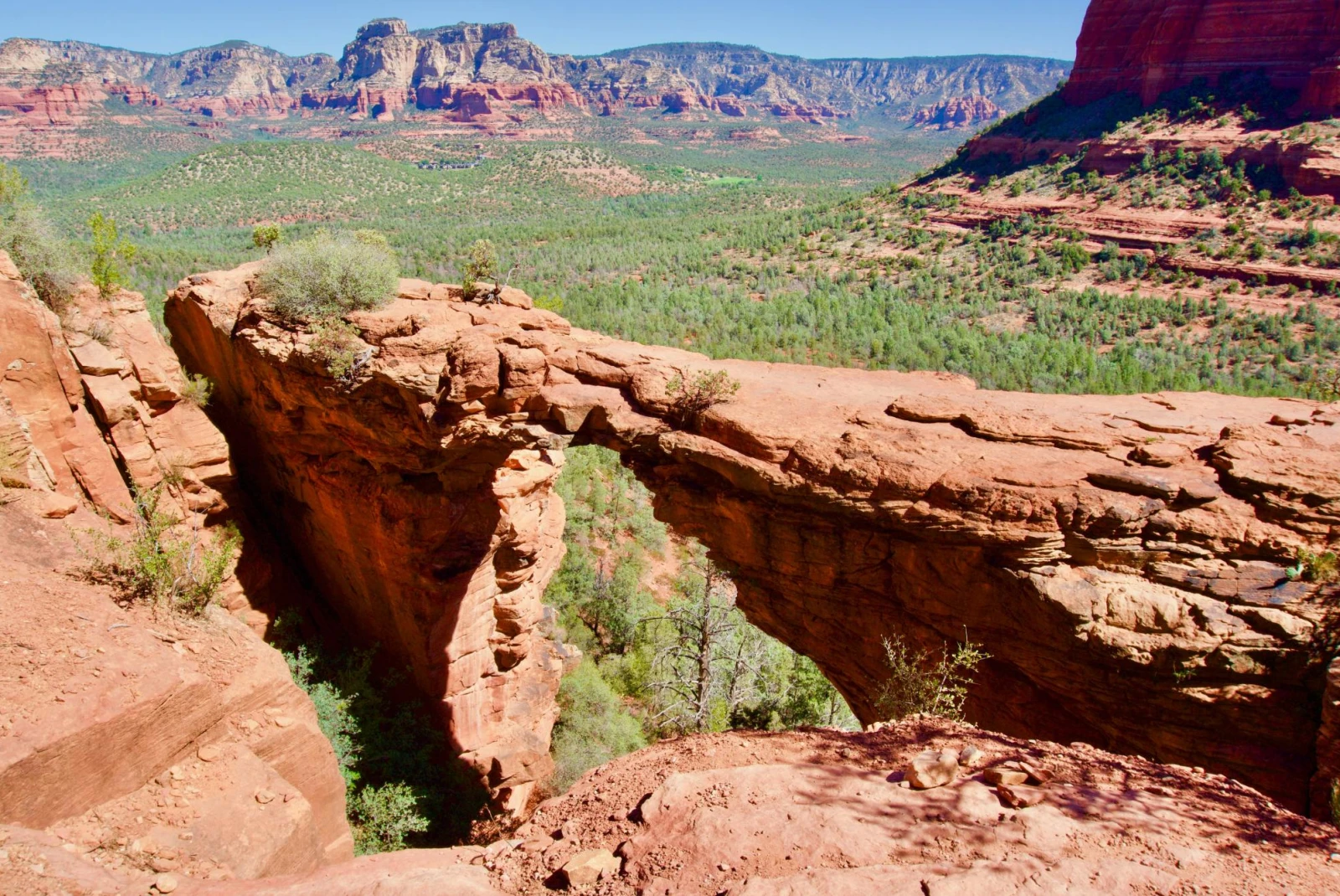 natural bridge made of red rock amidst canyon 